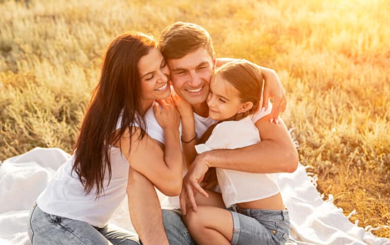 Cheerful family hugging in field